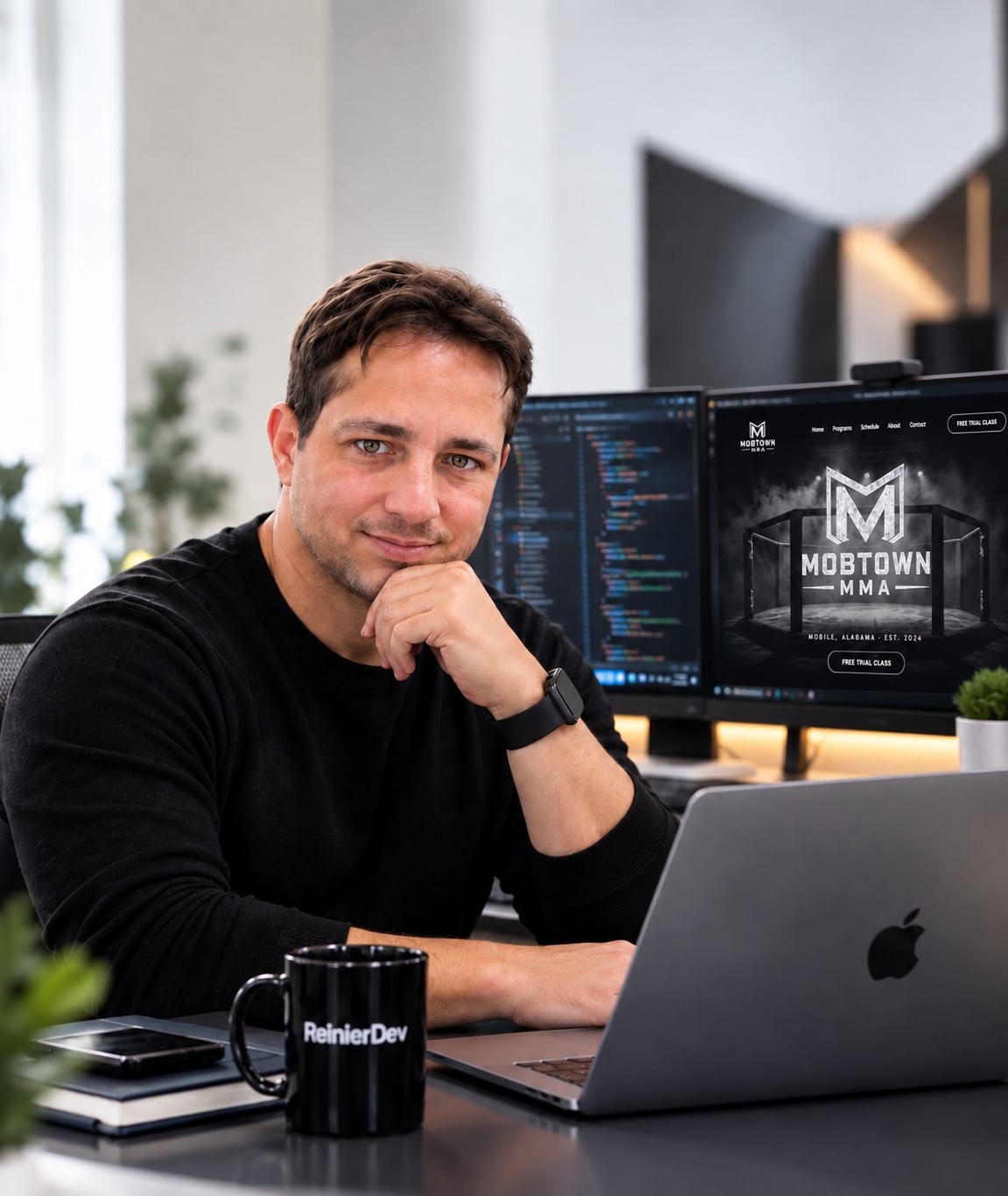 Reinier Moreno, desarrollador web, sonriendo frente a su laptop con pantallas de código detrás